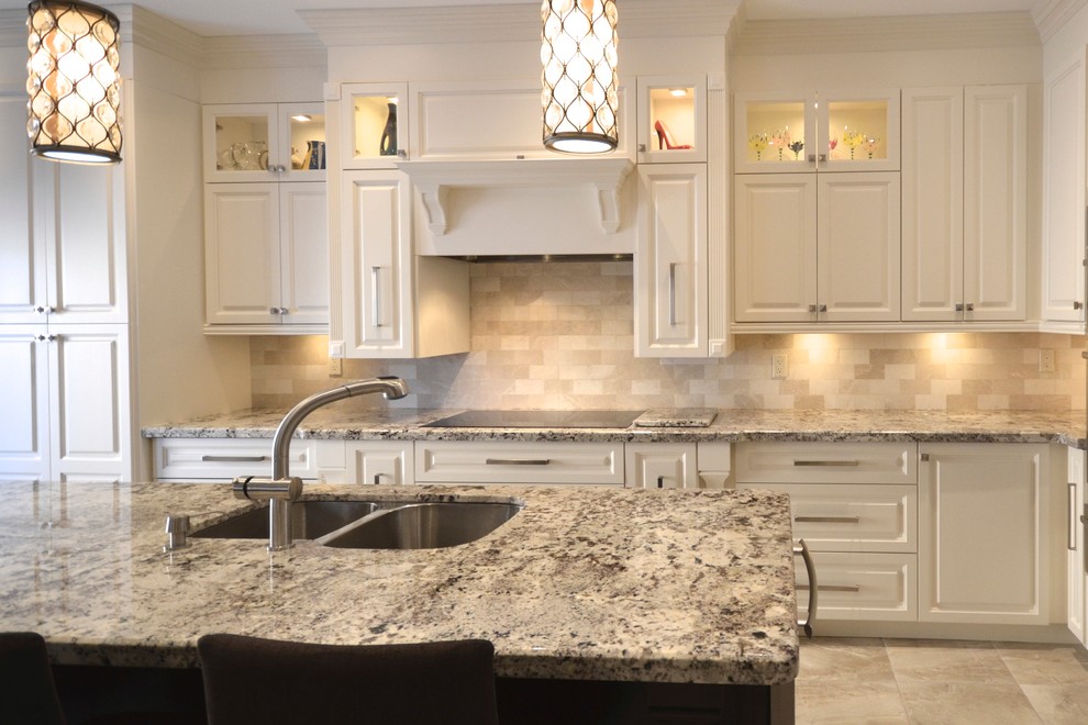 Example of a mid-sized transitional l-shaped porcelain tile open concept kitchen design in Toronto with an undermount sink, raised-panel cabinets, white cabinets, granite countertops, beige backsplash, stainless steel appliances and an island
