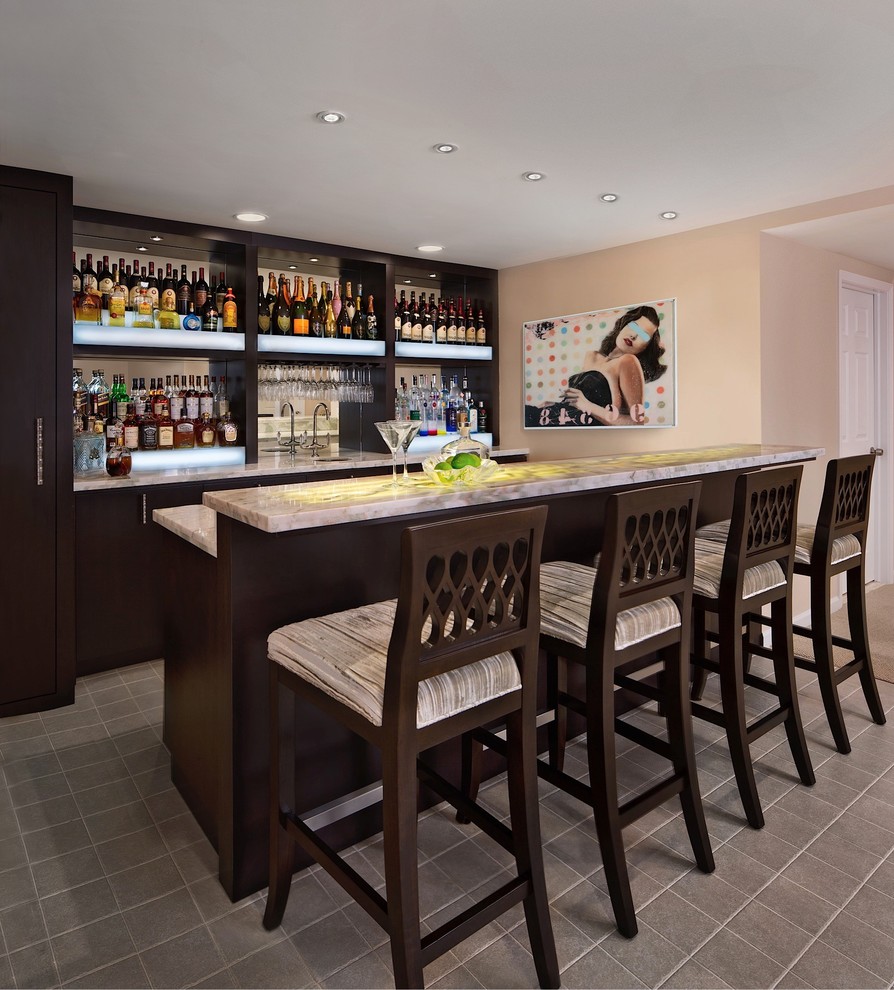 Transitional galley seated home bar in Detroit with an undermount sink, flat-panel cabinets, dark wood cabinets, onyx benchtops, ceramic floors, mirror splashback and grey floor.