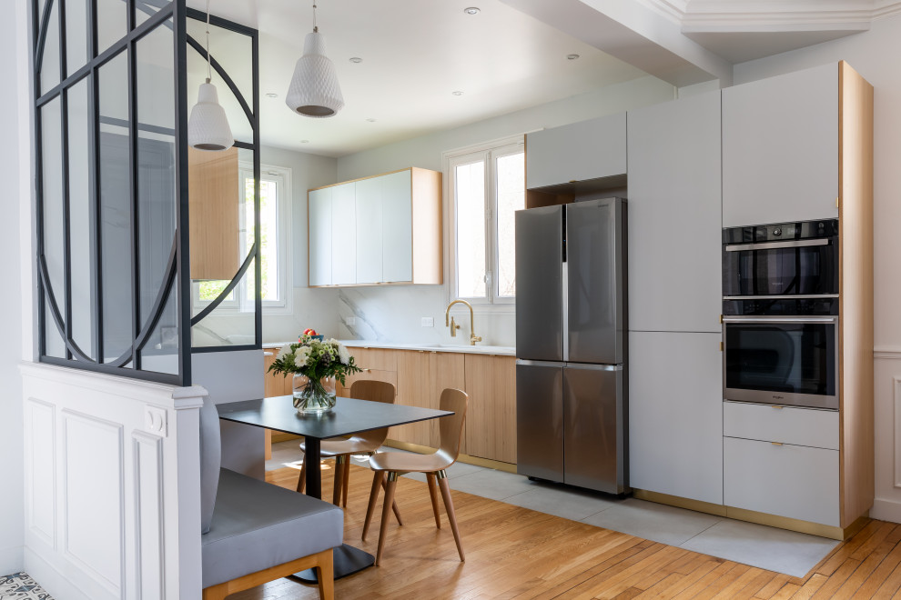 This is an example of an expansive u-shaped open plan kitchen in Paris with an undermount sink, beaded inset cabinets, grey cabinets, quartzite benchtops, white splashback, engineered quartz splashback, white appliances, ceramic floors, no island, grey floor, white benchtop and recessed.