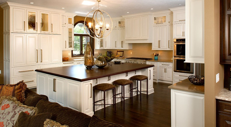 Example of a large l-shaped dark wood floor eat-in kitchen design in Miami with a farmhouse sink, beaded inset cabinets, white cabinets, solid surface countertops, beige backsplash, stainless steel appliances and an island