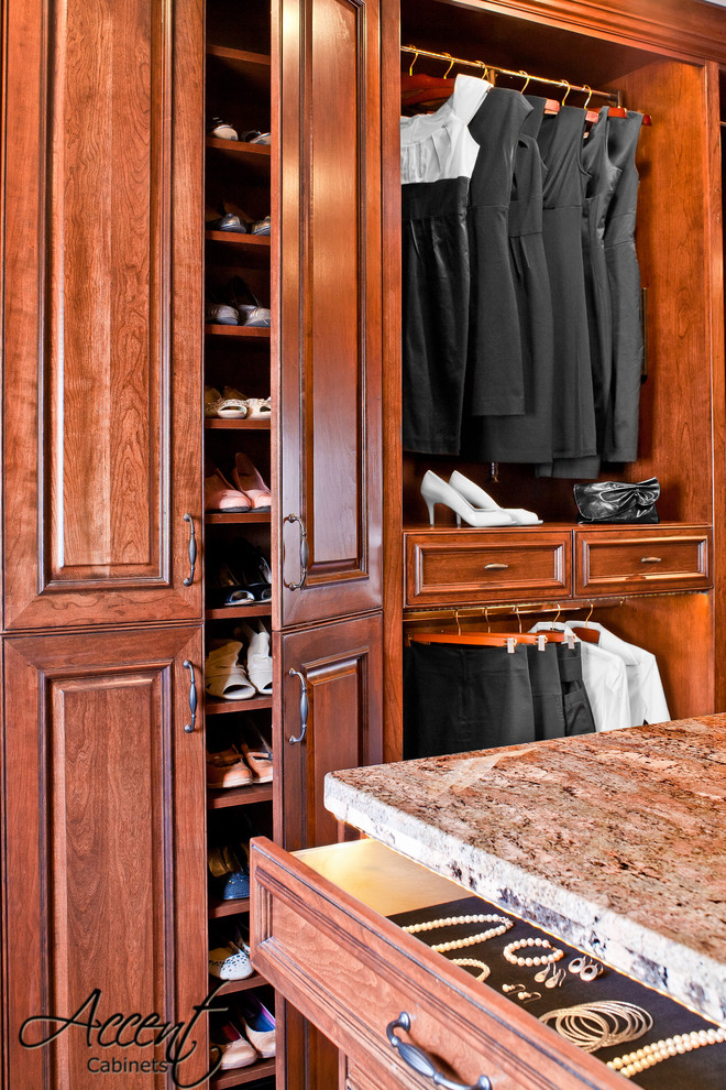 Inspiration for an expansive traditional gender-neutral dressing room in Houston with raised-panel cabinets, medium wood cabinets and light hardwood floors.