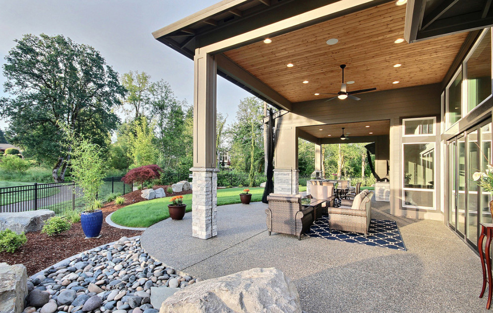 Cette photo montre une très grande terrasse arrière moderne avec un foyer extérieur, une dalle de béton et une extension de toiture.