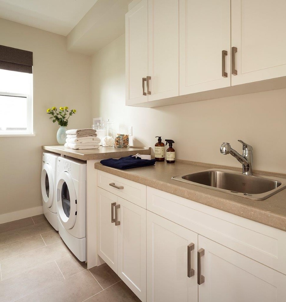 Inspiration for a mid-sized transitional galley dedicated laundry room in Vancouver with a drop-in sink, recessed-panel cabinets, white cabinets, beige walls, a side-by-side washer and dryer and beige benchtop.