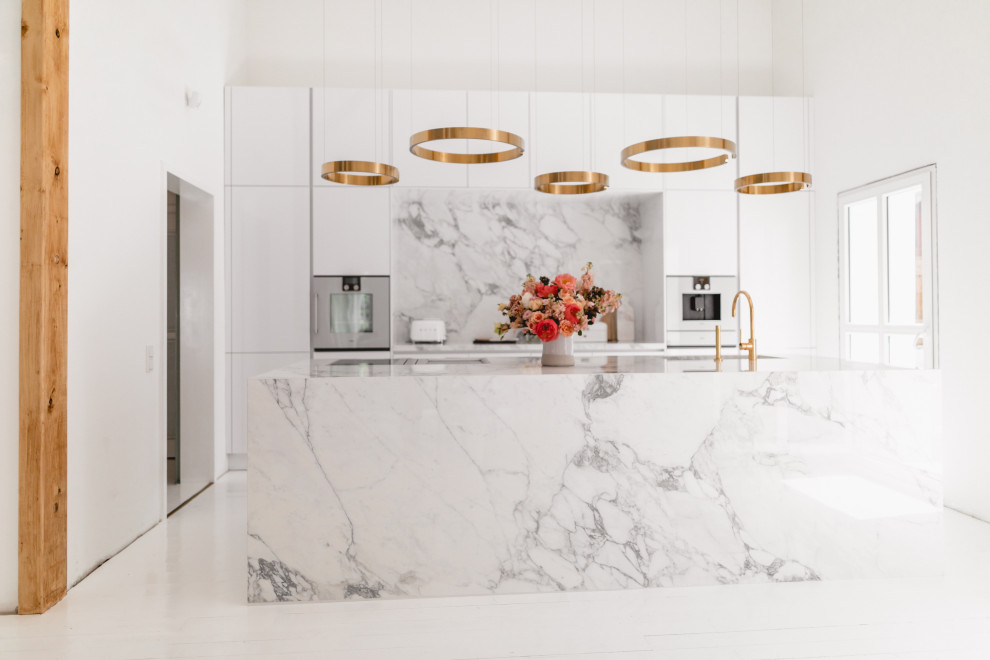 Large contemporary galley eat-in kitchen in Cologne with an integrated sink, flat-panel cabinets, white cabinets, marble benchtops, white splashback, ceramic splashback, white appliances, with island, white floor and white benchtop.
