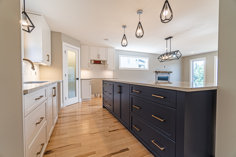 Inspiration for a mid-sized transitional light wood floor and beige floor eat-in kitchen remodel with an undermount sink, shaker cabinets, white cabinets, granite countertops, white backsplash, ceramic backsplash, an island and gray countertops