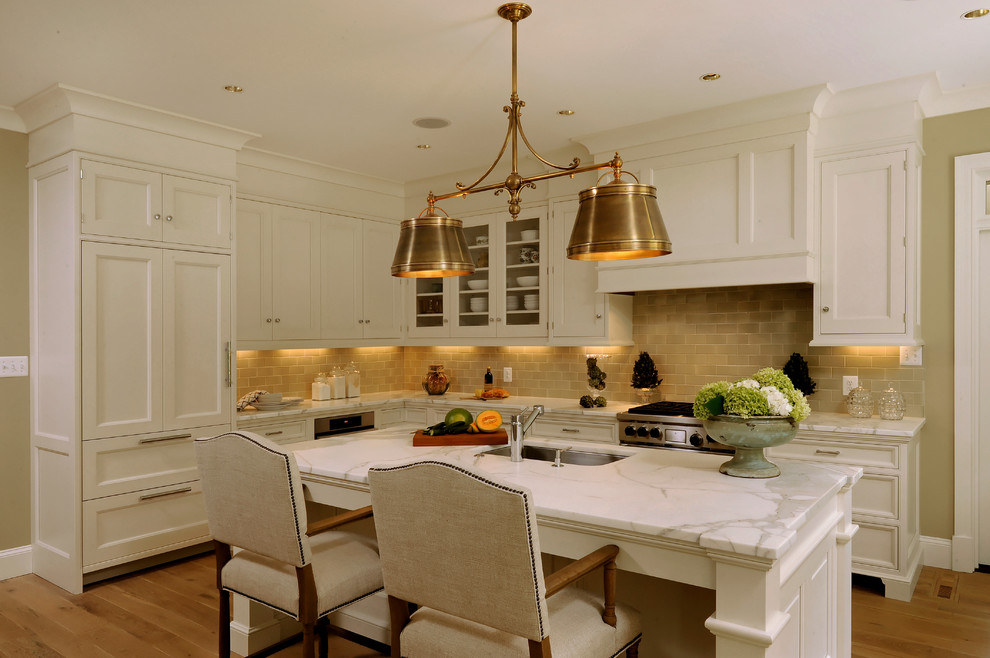 Design ideas for a mid-sized traditional l-shaped eat-in kitchen in DC Metro with an undermount sink, shaker cabinets, white cabinets, marble benchtops, beige splashback, subway tile splashback, stainless steel appliances, light hardwood floors and with island.