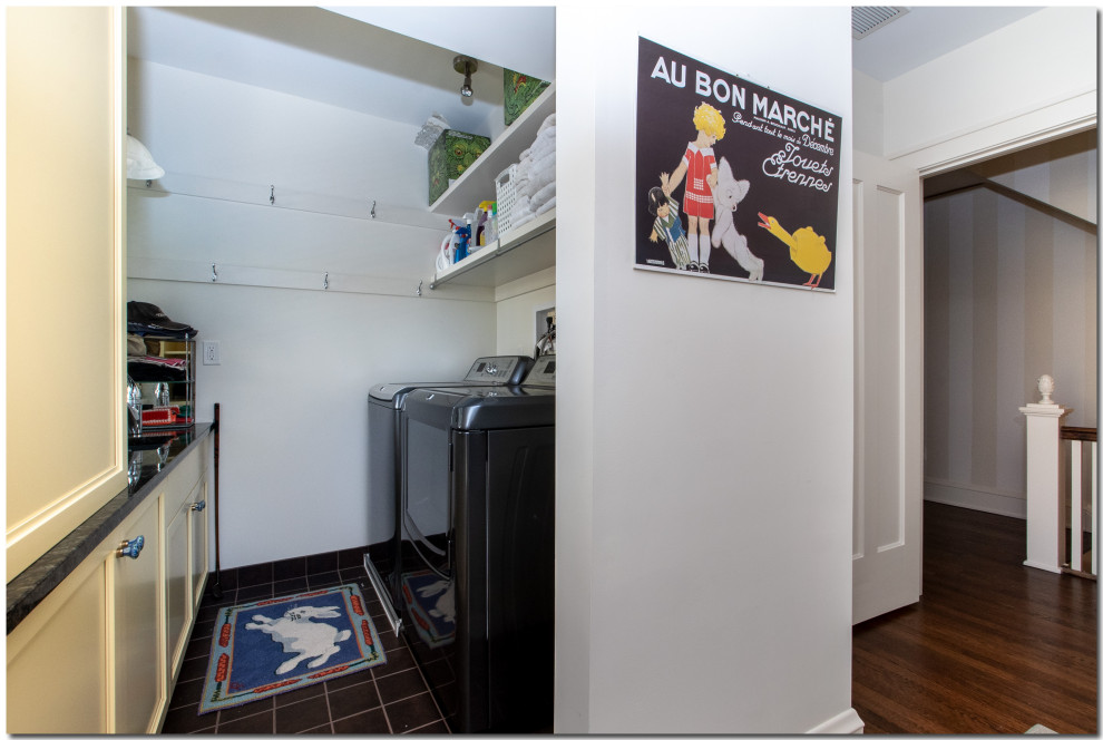This is an example of a small traditional galley utility room in Cleveland with recessed-panel cabinets, yellow cabinets, granite benchtops, white walls, porcelain floors, a side-by-side washer and dryer, black floor and black benchtop.