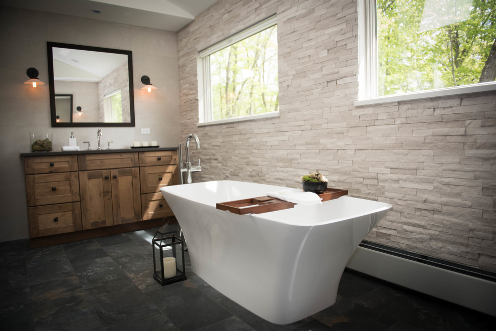 Large modern master bathroom in Other with shaker cabinets, medium wood cabinets, a freestanding tub, a corner shower, a one-piece toilet, white tile, stone tile, white walls, slate floors, a drop-in sink, solid surface benchtops, black floor, a hinged shower door and grey benchtops.