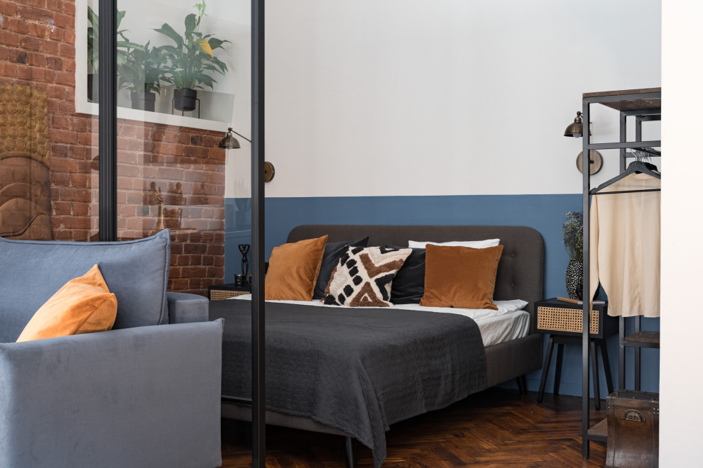 Свежая идея для дизайна: гостевая спальня среднего размера, (комната для гостей) в стиле лофт с синими стенами, паркетным полом среднего тона, кирпичными стенами и акцентной стеной - отличное фото интерьера
