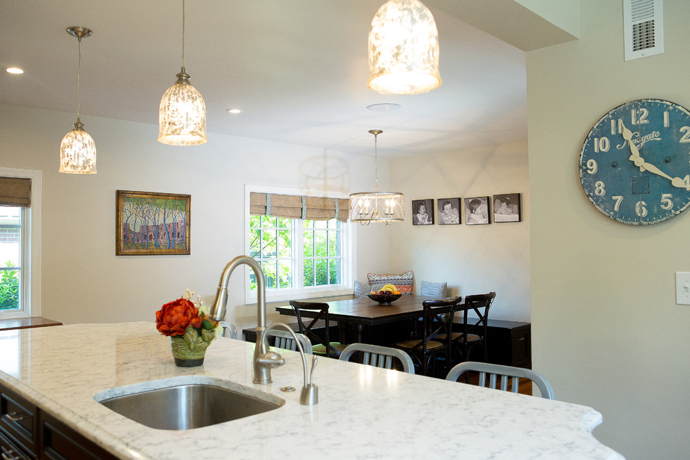 Example of a large transitional medium tone wood floor eat-in kitchen design with an undermount sink, recessed-panel cabinets, black cabinets, quartz countertops, brick backsplash, stainless steel appliances and an island