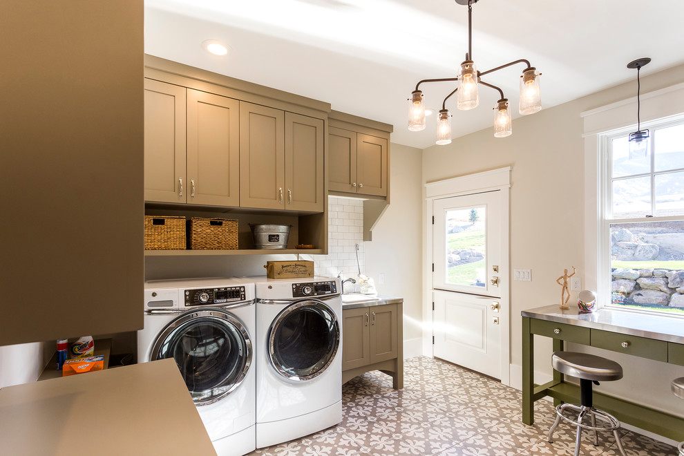This is an example of a large arts and crafts galley utility room in Salt Lake City with a drop-in sink, raised-panel cabinets, brown cabinets, stainless steel benchtops, white walls, ceramic floors and a side-by-side washer and dryer.
