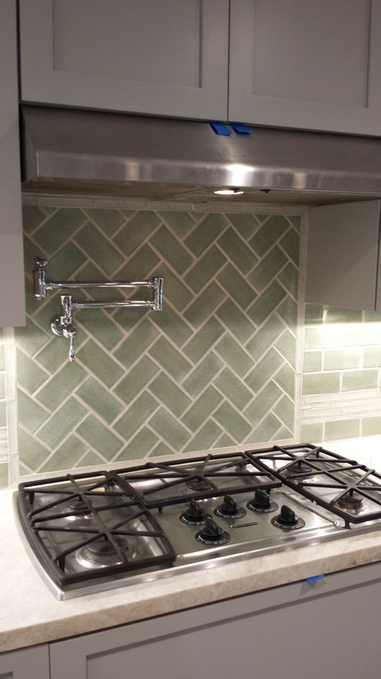 Inspiration for a mid-sized transitional galley medium tone wood floor eat-in kitchen remodel with a farmhouse sink, shaker cabinets, white cabinets, granite countertops, green backsplash, glass tile backsplash, stainless steel appliances and no island