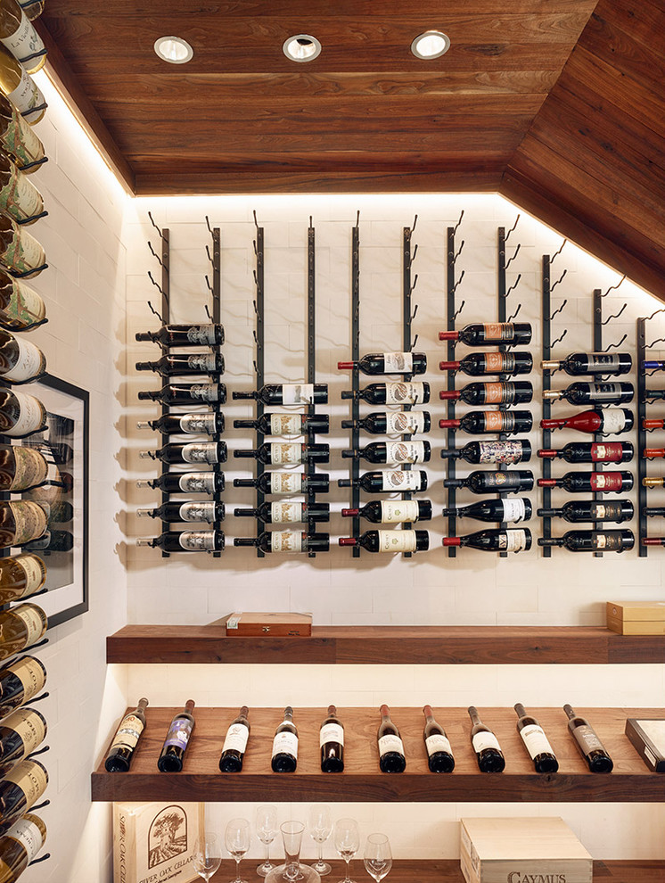 Photo of a mid-sized contemporary wine cellar in Austin with light hardwood floors, display racks and beige floor.