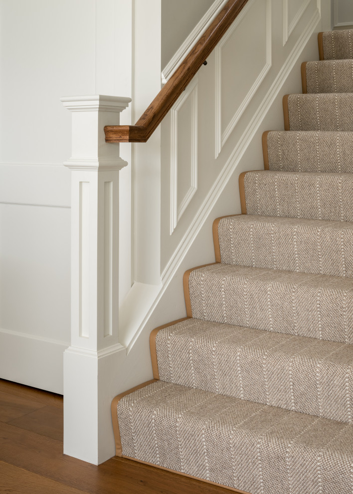 Staircase - transitional carpeted u-shaped wood railing and wainscoting staircase idea in Burlington with carpeted risers