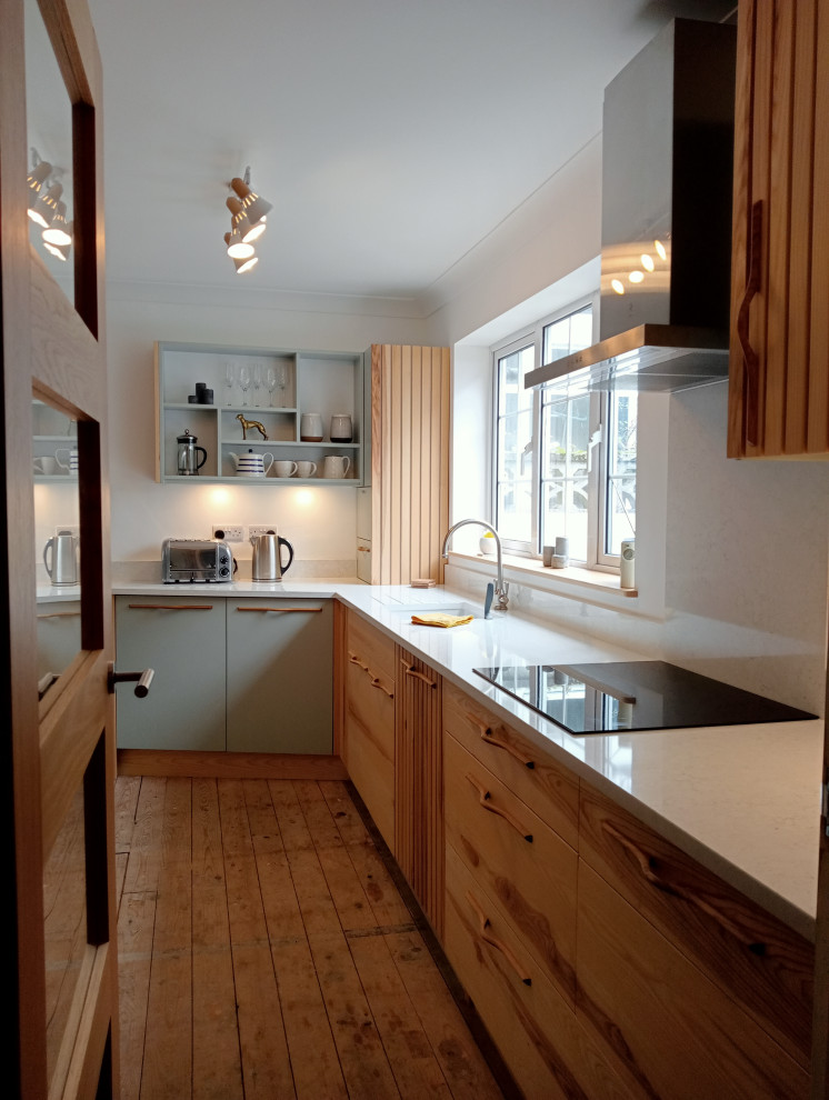 Inspiration for a mid-sized contemporary l-shaped eat-in kitchen in Cornwall with a double-bowl sink, flat-panel cabinets, light wood cabinets, quartz benchtops, white splashback, engineered quartz splashback, stainless steel appliances, light hardwood floors, no island and white benchtop.