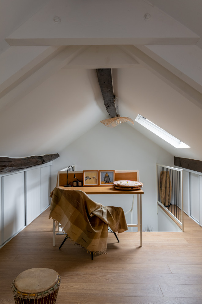 Mittelgroßes Mediterranes Arbeitszimmer mit Arbeitsplatz, weißer Wandfarbe, hellem Holzboden, Einbau-Schreibtisch und freigelegten Dachbalken in Paris