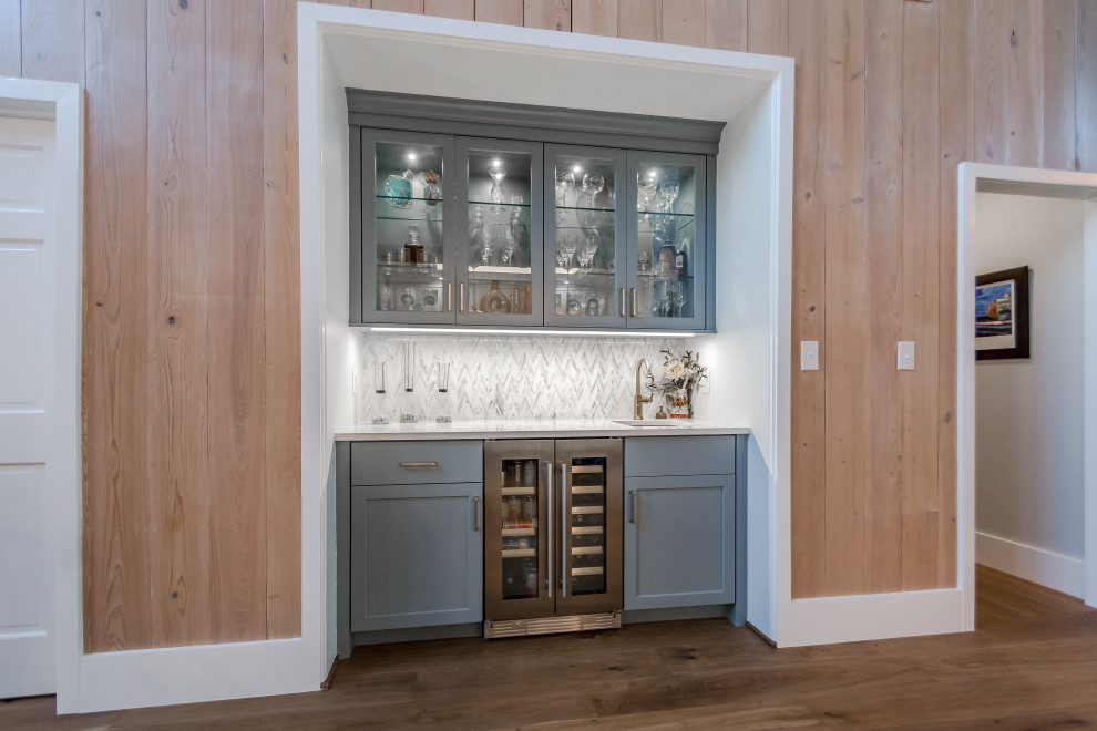 Diseño de bar en casa en U clásico renovado pequeño con armarios con paneles empotrados, salpicadero multicolor, suelo marrón, encimeras blancas y puertas de armario grises