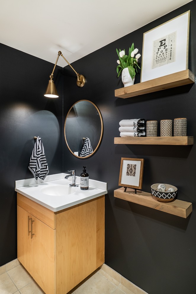 Photo of a mid-sized contemporary powder room in Phoenix with flat-panel cabinets, light wood cabinets, black walls, an integrated sink and beige floor.