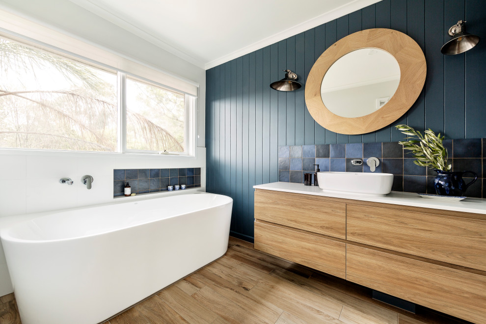 Design ideas for a contemporary master bathroom in Melbourne with flat-panel cabinets, light wood cabinets, a freestanding tub, multi-coloured tile, green walls, a vessel sink, beige floor and white benchtops.