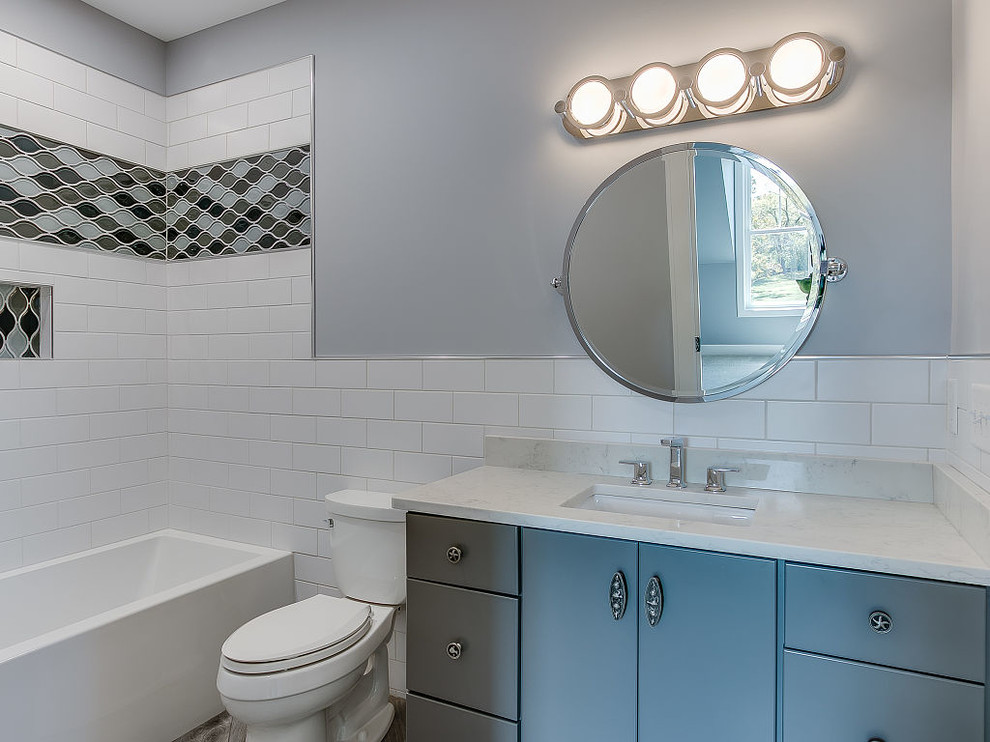 Inspiration for a mid-sized transitional kids' white tile and subway tile alcove bathtub remodel with gray cabinets, a two-piece toilet, flat-panel cabinets, gray walls, an undermount sink, quartzite countertops and white countertops