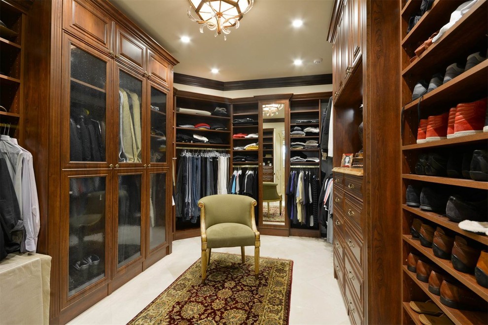 Inspiration for a mid-sized mediterranean men's walk-in wardrobe in Miami with raised-panel cabinets, dark wood cabinets, carpet and white floor.