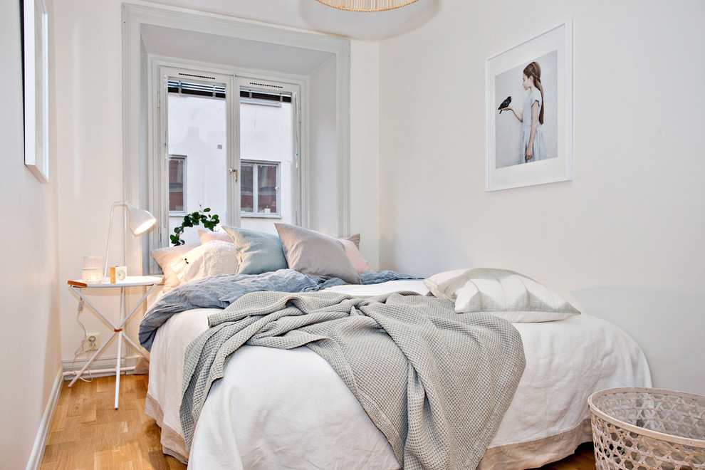 Photo of a small scandinavian master bedroom in Stockholm with white walls, medium hardwood floors and no fireplace.