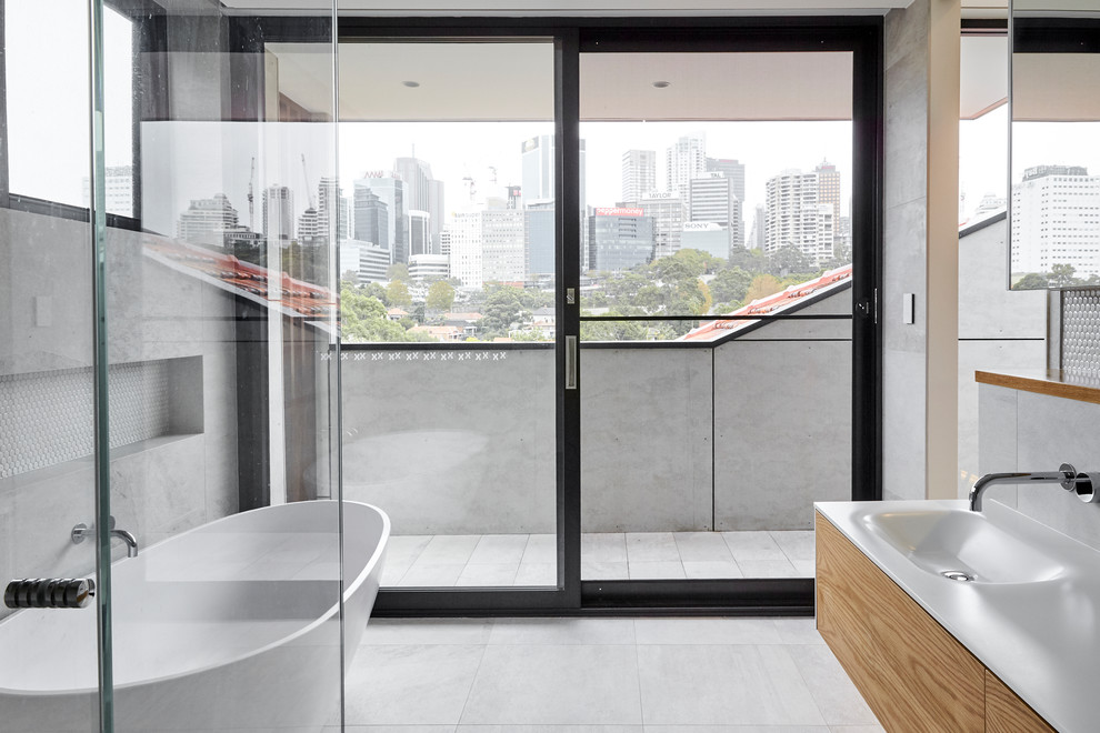 Contemporary 3/4 bathroom in Sydney with flat-panel cabinets, medium wood cabinets, a freestanding tub, gray tile, white tile, mosaic tile, grey walls, an integrated sink, grey floor and white benchtops.