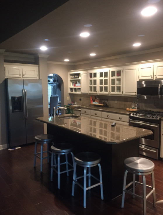 Enclosed kitchen - mid-sized transitional l-shaped dark wood floor and brown floor enclosed kitchen idea with an undermount sink, raised-panel cabinets, white cabinets, granite countertops, gray backsplash, glass tile backsplash, stainless steel appliances and an island