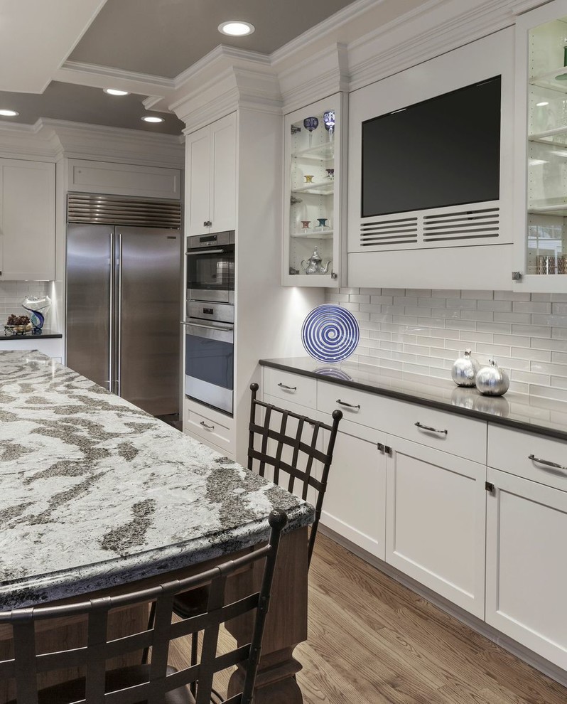 Kitchen pantry - large transitional light wood floor kitchen pantry idea in Cleveland with white backsplash, glass tile backsplash, stainless steel appliances and an island
