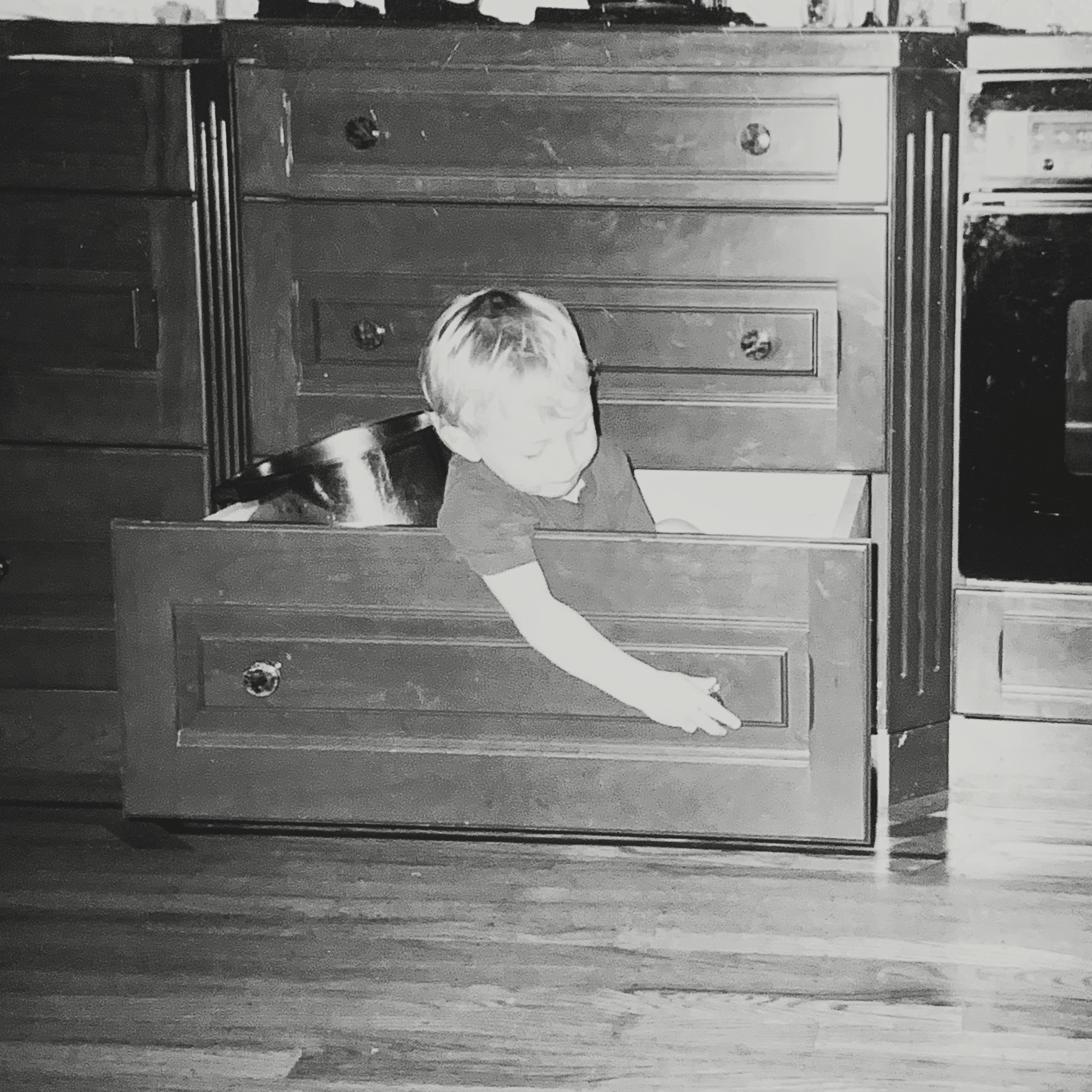 Lead designer Eric Sundborg at 2 years old, inspecting the hardware of a drawer he is sitting in.
