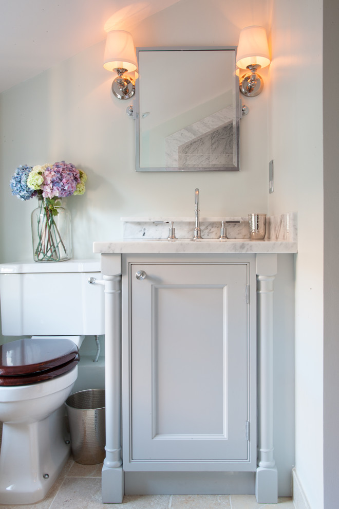 This is an example of a traditional powder room in London with beaded inset cabinets, white cabinets, white walls, marble benchtops and white benchtops.