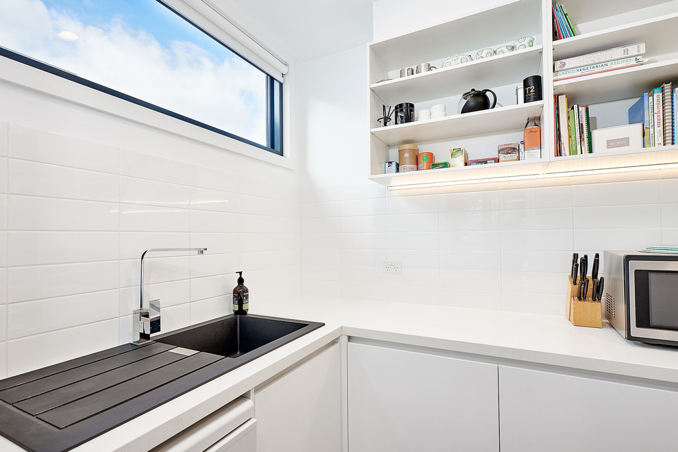Small contemporary u-shaped kitchen pantry in Melbourne with a single-bowl sink, open cabinets, white cabinets, quartz benchtops, white splashback, porcelain splashback, dark hardwood floors and no island.