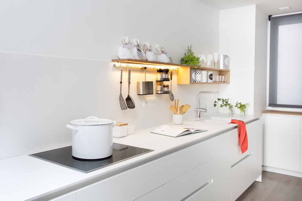 Photo of a small scandinavian single-wall open plan kitchen in Barcelona with no island, flat-panel cabinets and white cabinets.