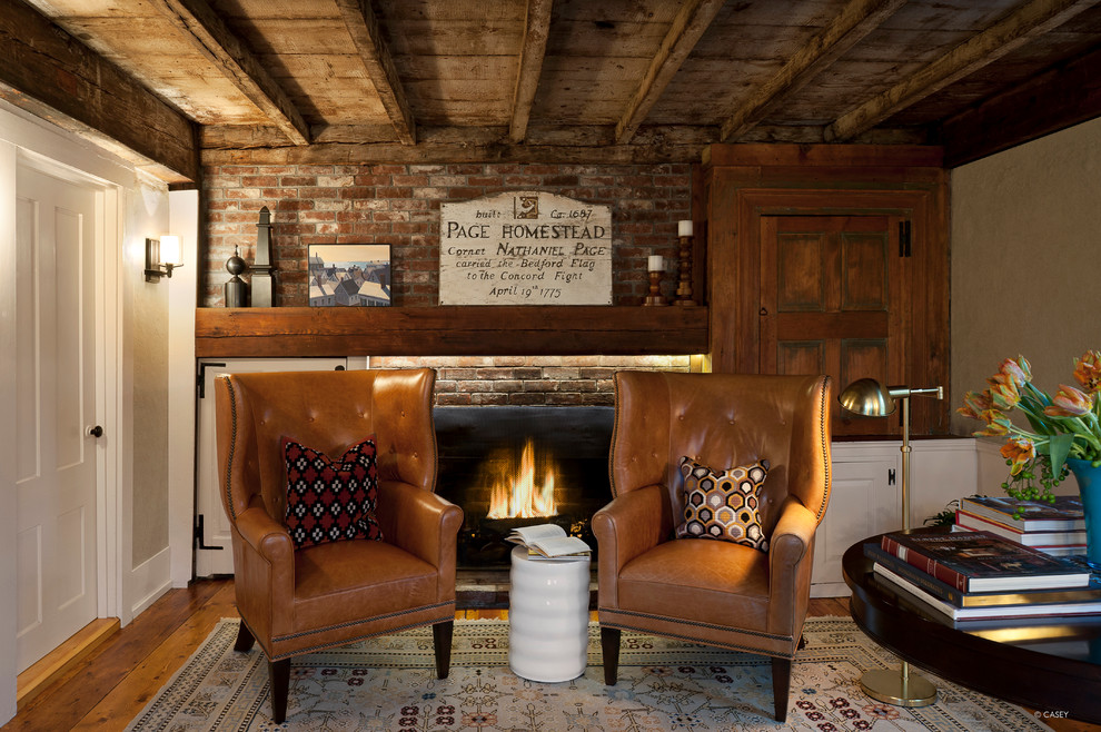 Inspiration for a mid-sized country study room in Boston with a brick fireplace surround, white walls, medium hardwood floors, a standard fireplace and a freestanding desk.