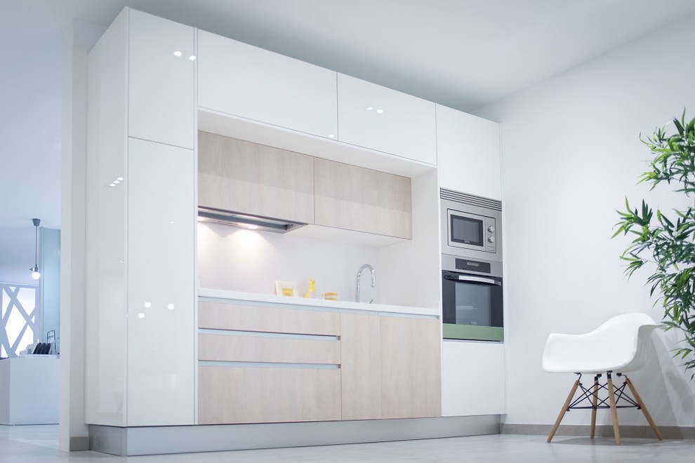 Foto de cocina lineal nórdica de tamaño medio abierta sin isla con fregadero de un seno, armarios con paneles lisos, puertas de armario de madera clara, salpicadero blanco y electrodomésticos de acero inoxidable