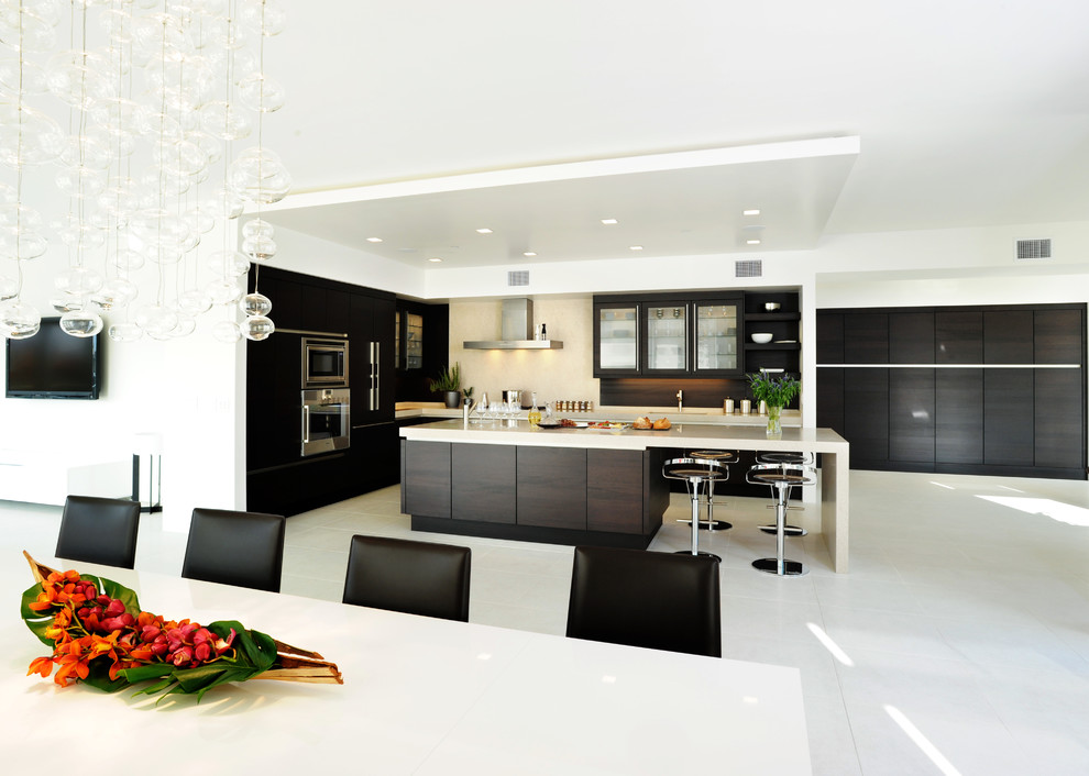 This is an example of a large contemporary l-shaped open plan kitchen in San Francisco with flat-panel cabinets, panelled appliances, dark wood cabinets, quartz benchtops, beige splashback, stone tile splashback and with island.