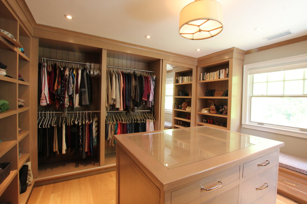 Photo of a large traditional gender-neutral walk-in wardrobe in New York with light wood cabinets, light hardwood floors and open cabinets.