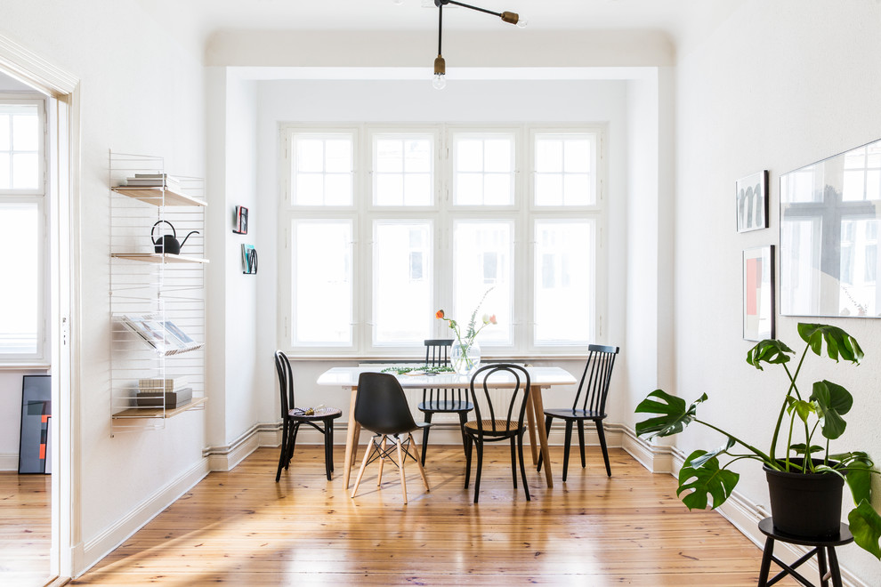 Inspiration for a mid-sized scandinavian separate dining room in Berlin with white walls, light hardwood floors and brown floor.