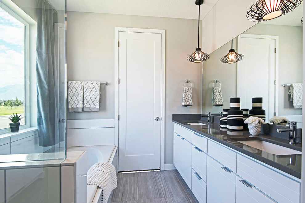 Inspiration for an arts and crafts master bathroom in Salt Lake City with flat-panel cabinets, white cabinets, a drop-in tub, a corner shower, a one-piece toilet, white tile, ceramic tile, grey walls, ceramic floors, an undermount sink and engineered quartz benchtops.