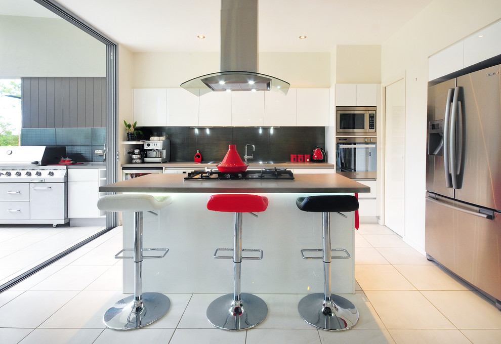 This is an example of a small contemporary u-shaped open plan kitchen in Brisbane with a drop-in sink, white cabinets, quartz benchtops, black splashback, porcelain splashback, stainless steel appliances, porcelain floors, with island and flat-panel cabinets.