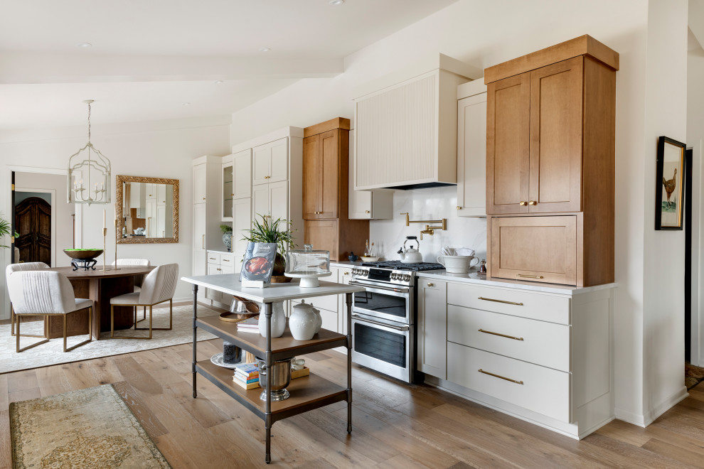 Inspiration for a mid-sized transitional galley medium tone wood floor, brown floor and vaulted ceiling eat-in kitchen remodel in Minneapolis with an undermount sink, shaker cabinets, quartz countertops, white backsplash, subway tile backsplash, stainless steel appliances, an island and white countertops