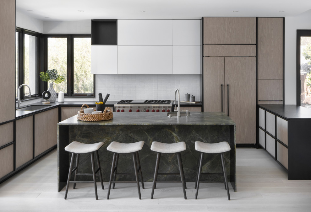 Photo of a large contemporary l-shaped eat-in kitchen in Boston with flat-panel cabinets, light wood cabinets, marble benchtops, white splashback, panelled appliances, with island, white floor and green benchtop.