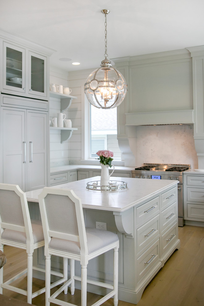Design ideas for a large transitional u-shaped eat-in kitchen in Milwaukee with recessed-panel cabinets, quartz benchtops, white splashback, panelled appliances, with island, a farmhouse sink, white cabinets, stone slab splashback, light hardwood floors and beige floor.