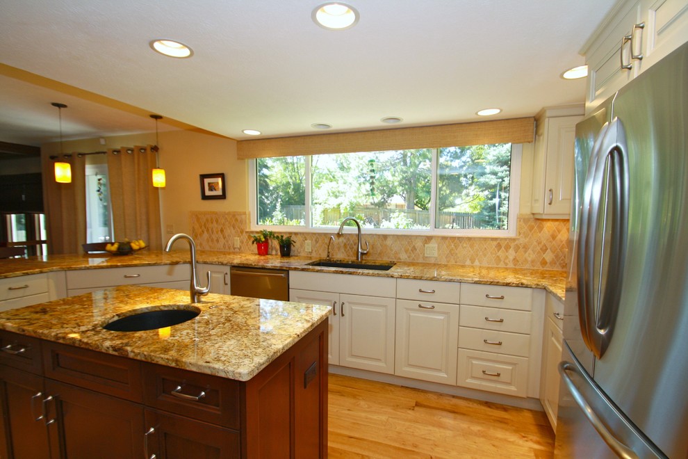 Inspiration for a large transitional u-shaped medium tone wood floor eat-in kitchen remodel in Denver with an undermount sink, raised-panel cabinets, white cabinets, granite countertops, beige backsplash, ceramic backsplash, stainless steel appliances and an island