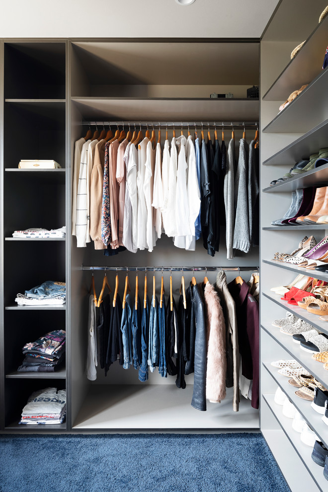 Design ideas for an industrial gender-neutral walk-in wardrobe in Melbourne with open cabinets, black cabinets, carpet and blue floor.