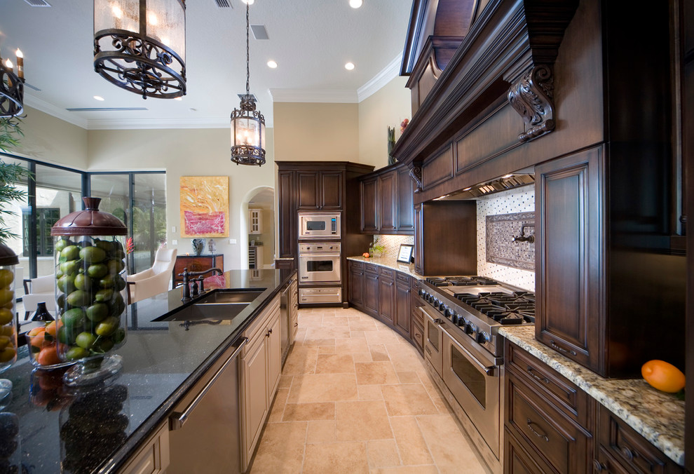 Photo of a mediterranean kitchen in Orlando with a double-bowl sink, dark wood cabinets, multi-coloured splashback, stainless steel appliances and with island.