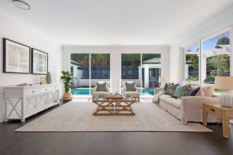 This is an example of a large beach style open concept living room in Sydney with white walls and dark hardwood floors.