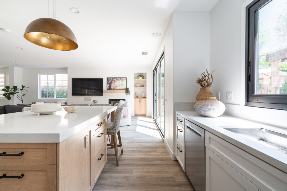 Large beach style u-shaped vinyl floor and beige floor open concept kitchen photo in Denver with an undermount sink, recessed-panel cabinets, light wood cabinets, quartz countertops, white backsplash, ceramic backsplash, stainless steel appliances, an island and white countertops