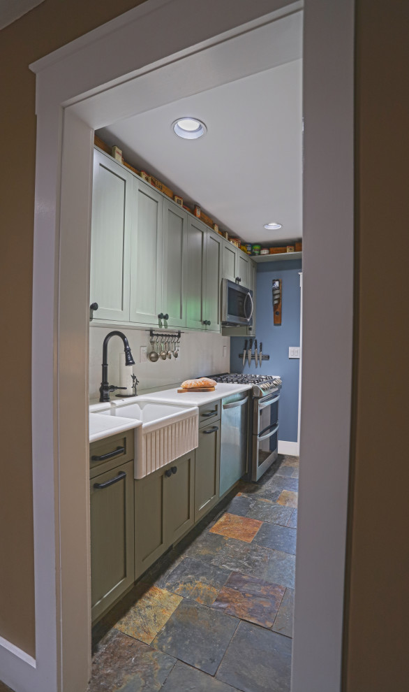 This is an example of a mid-sized country u-shaped eat-in kitchen in New York with a farmhouse sink, shaker cabinets, green cabinets, quartz benchtops, white splashback, engineered quartz splashback, stainless steel appliances, slate floors, no island, multi-coloured floor and white benchtop.