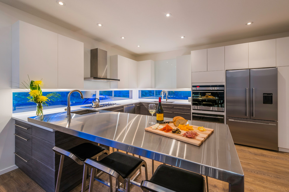Inspiration for a contemporary u-shaped eat-in kitchen in Vancouver with an undermount sink, flat-panel cabinets, white cabinets, stainless steel appliances, medium hardwood floors and a peninsula.